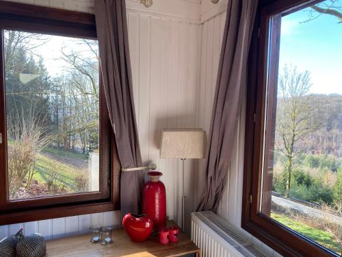 a red vase sitting on a table next to a window at Le Cap Vert in Rochehaut
