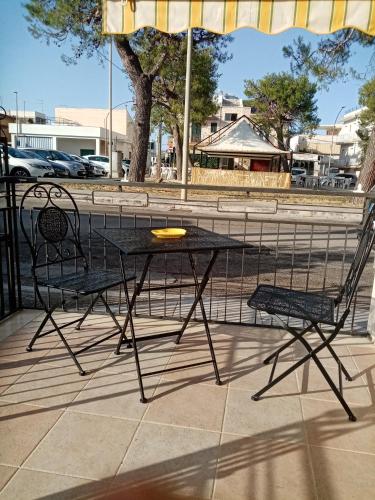 a black table and two chairs under an umbrella at MAGNA GRECIA SEA HOME in Torre Canne