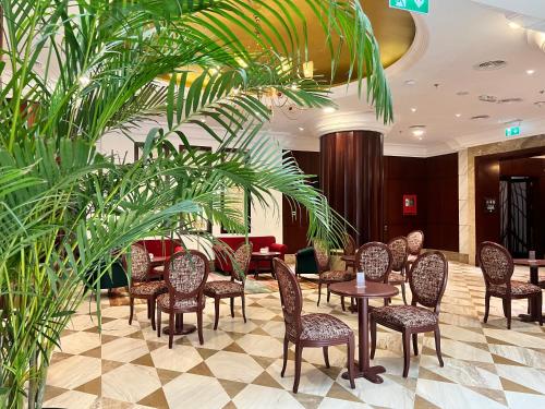 a lobby with tables and chairs and plants at City Seasons Suites in Dubai