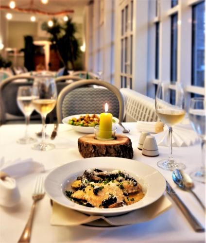 a table with a plate of food and glasses of wine at Waldhotel am See Berlin-Schmöckwitz in Berlin