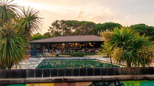 a pool in front of a restaurant with palm trees at RAS L'BOL in Olmeto