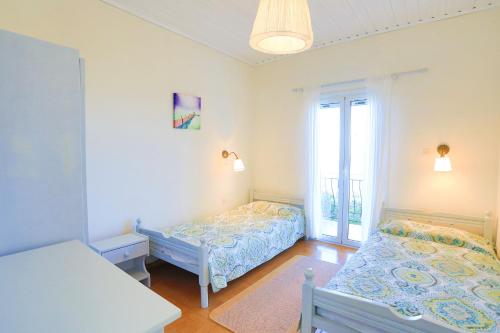 een slaapkamer met 2 bedden en een raam bij Antigoni Villas in Longós