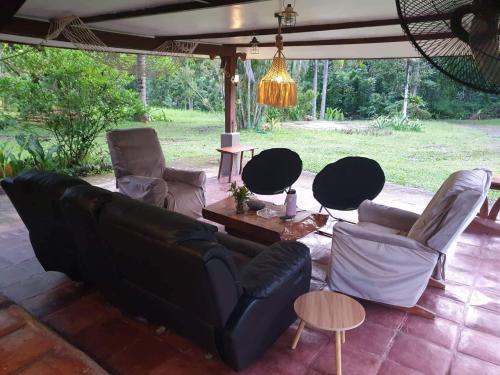 sala de estar con sofá negro y sillas en The Farm, en Puerto Princesa City