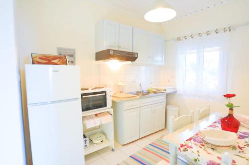 een witte keuken met een tafel en een witte koelkast bij Antigoni Villas in Longós