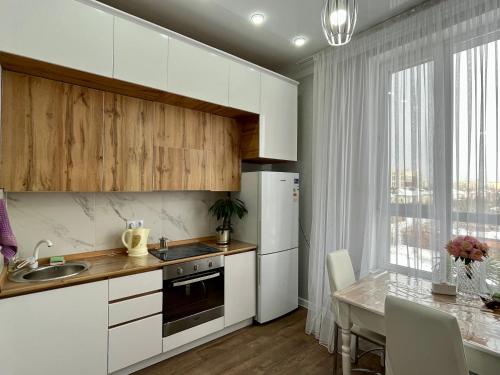 een keuken met witte kasten en een tafel met een eetkamer bij Квартира ЖК Apple city in Astana