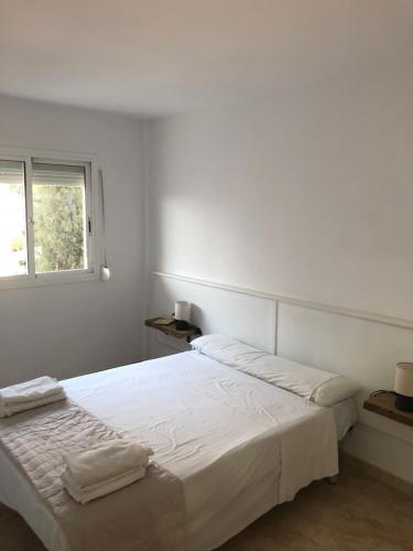 - une chambre blanche avec un lit et des serviettes dans l'établissement Apartamento SalouMar, à Salou