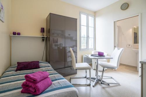 1 dormitorio con 1 cama, mesa y sillas en Les Jardins De La Seugne, en Jonzac
