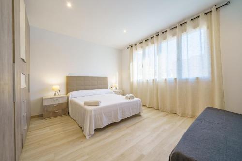ein Schlafzimmer mit einem weißen Bett und einem großen Fenster in der Unterkunft HomeHolidaysRentals Music - Costa Barcelona in Pineda de Mar