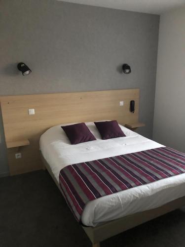 a bedroom with a large bed with a wooden headboard at Rev'hotel in Ribérac