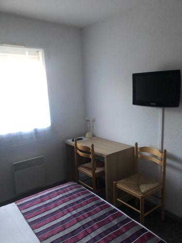 a room with a table and two chairs and a television at Rev'hotel in Ribérac