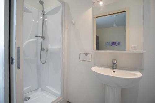 biała łazienka z umywalką i prysznicem w obiekcie Les Jardins De La Seugne w mieście Jonzac