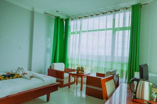 a bedroom with a bed and chairs and a window at Greenlight Hotel in Dar es Salaam