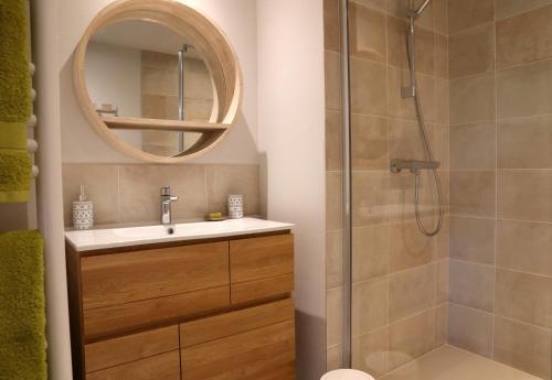 a bathroom with a sink and a shower with a mirror at Des Feuilles et Des Hiboux in Plescop