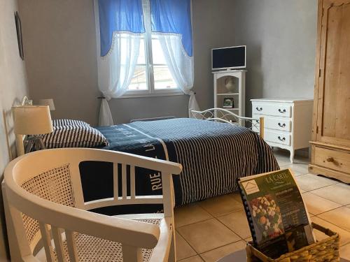 a bedroom with a bed and a chair and a window at Les Lavandières in Saint-Hilaire-la-Palud