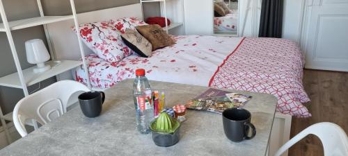 een tafel met een fles erop met een bed bij Vittel Studio neuf en Centre-ville idéal curiste in Vittel