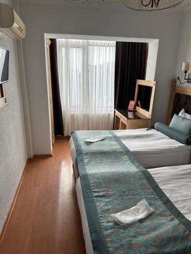 イスタンブールにあるブルー トゥアナ ホテルのベッド2台と鏡が備わるホテルルームです。