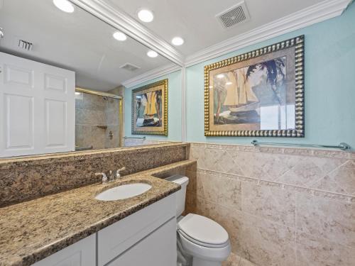 ein Badezimmer mit einem Waschbecken, einem WC und einem Gemälde in der Unterkunft Estero Island Beach Villas 706, 2 BR, Penthouse, Gulf Front, Pool, Sleeps 6 in Fort Myers Beach