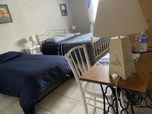 a bedroom with a bed and a table with a lamp at Les Lavandières in Saint-Hilaire-la-Palud