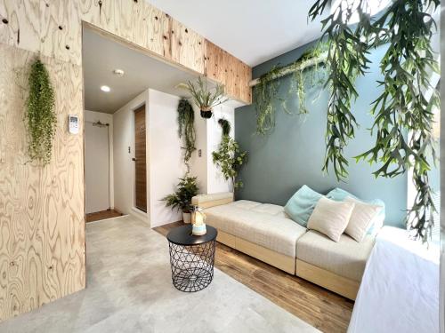 ein Wohnzimmer mit Sofa und einigen Pflanzen in der Unterkunft 365BASE outdoor hostel in Hamamatsu