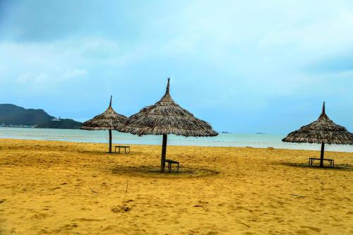 four straw umbrellas on a beach with the ocean at Sông Suối Homestay in Quy Nhon