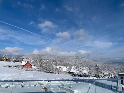 a snow covered mountain with houses and a red house at Gîte "Villa Belle Vie" in Labaroche