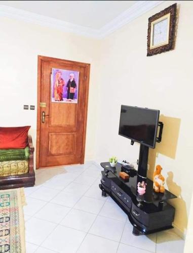 uma sala de estar com uma televisão de ecrã plano e uma porta em Appartement à louer à Tadamon 2 Hay Salam / Agadir em Agadir