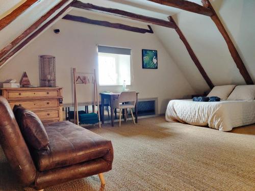 ein Schlafzimmer mit einem Bett und einem Tisch im Dachgeschoss in der Unterkunft Maison d'Hôtes La Grange in Salers