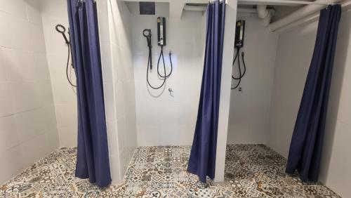 a bathroom with blue shower curtains and a tile floor at Glur Hostel Pattaya Walking Street in Pattaya Central