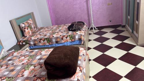 a bedroom with two beds and a checkered floor at 84 جسر السويس الدور 6 in Cairo