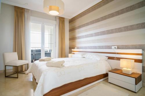 - une chambre avec un grand lit et un mur rayé dans l'établissement Los Robles de Los Arqueros golf 3 bedrooms apartment., à Benahavís