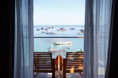 a window with two chairs and a view of the water at Escape Bajo in Labuan Bajo