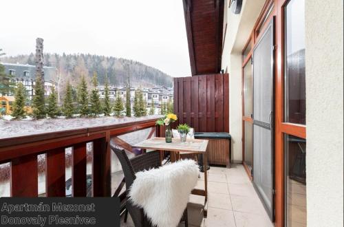 a balcony with a table and chairs and a view of a mountain at APARTMÁN MEZONET DONOVALY Plesnivec in Donovaly
