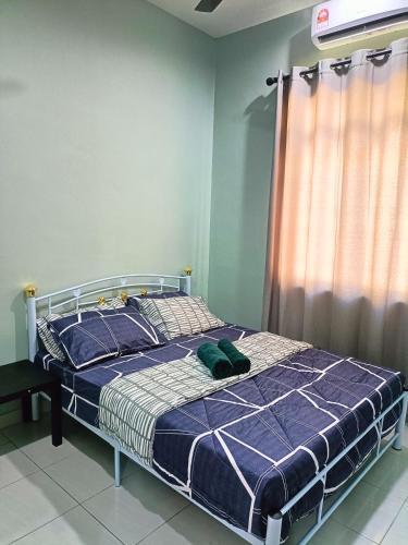 a bedroom with a bed with a blue comforter and a window at NazLa Homestay Pendang in Pendang