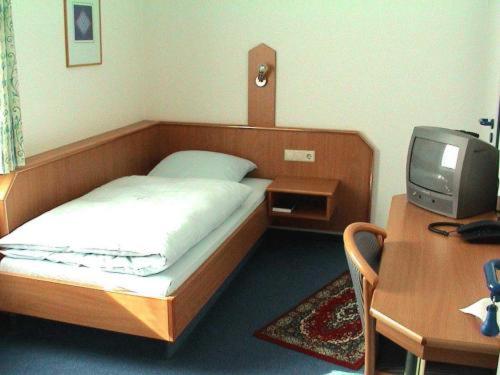 Schlafzimmer mit einem Bett und einem Schreibtisch mit einem TV in der Unterkunft Hotel Garni Kreuzäcker in Ulm