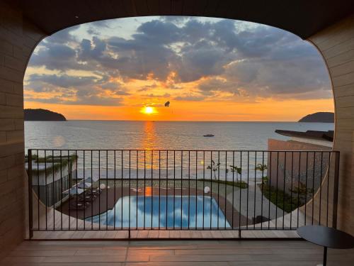a view of a sunset from a balcony with a swimming pool at PARKROYAL Langkawi Resort in Pantai Cenang