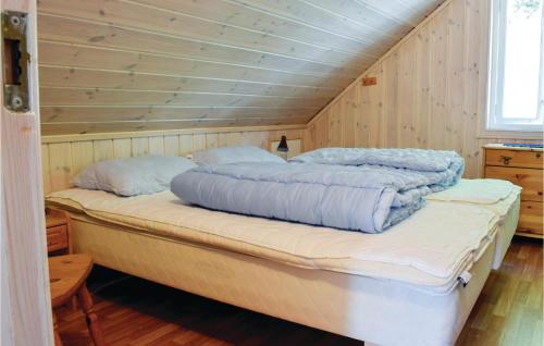 uma cama grande num quarto com paredes de madeira em Cozy Home In Lyngdal With Kitchen em Lyngdal