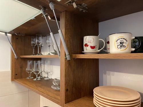 une étagère en bois avec des tasses, des verres et des assiettes dans l'établissement Prestige Apartment Teslic, à Teslić