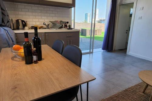 a kitchen with a wooden table with wine bottles on it at דירת גג WOW מול רוטשילד תל אביב in Tel Aviv