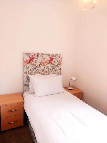 a bedroom with a white bed with a floral headboard at Grains Bar Hotel in Oldham