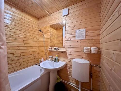 a wooden bathroom with a sink and a bath tub at Chalet Nomad in Petroşani