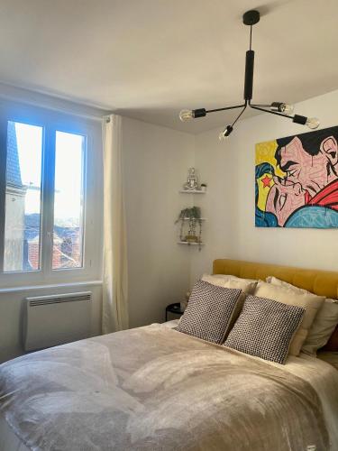 une chambre avec un lit avec un tableau sur le mur dans l'établissement Les mouettes de Trouville, à Trouville-sur-Mer
