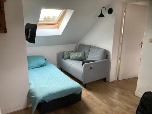 une chambre avec un lit, un canapé et une fenêtre dans l'établissement LE CLOS DE BEAUCHAMP LE GRENIER DE BEAUCHAMP 3 vélos sont disponibles gratuitement, à Saint-Valery-sur-Somme