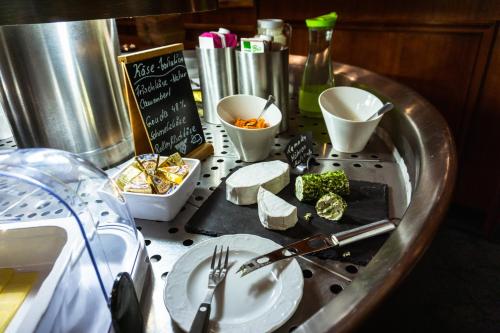 a table topped with plates and utensils and cheese at Berghotel Steiger - Erzgebirge in Schneeberg