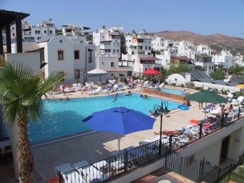 a view of a swimming pool with umbrellas and buildings at Ozukara Apart 2 in Gümbet