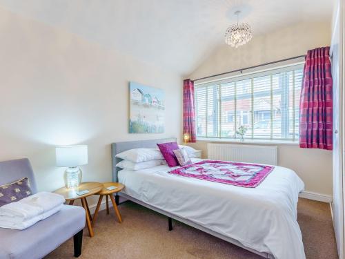 a bedroom with a bed and a chair and a window at Mikro Miramar - Cottage in Pevensey