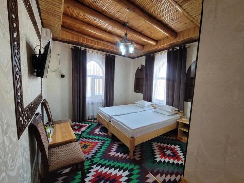 a bedroom with a bed and a table and a chair at Khiva Siyovush Hotel in Khiva