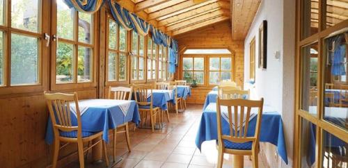 un comedor con mesas y sillas azules y ventanas en Haus Carola, en Bad Füssing