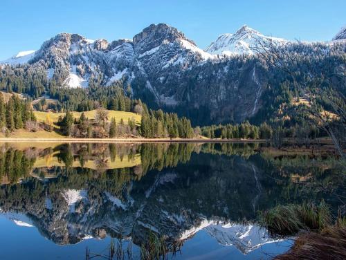 a mountain reflection in a lake with mountains in the background at Chalet mit Kino und Jacuzzi in Gsteig b. Gstaad in Gsteig