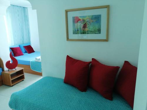 um quarto com uma cama com almofadas vermelhas e azuis em Hotel Veronika em Kranevo