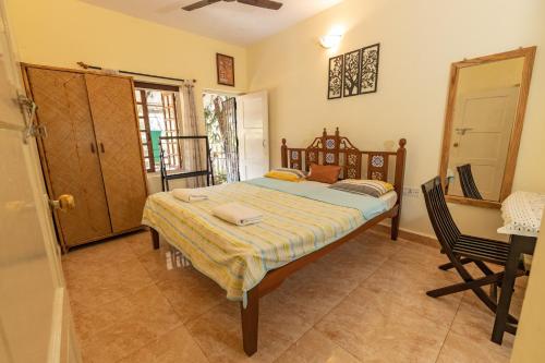 a bedroom with a bed and a table and a chair at Beach Village Holiday Homes Goa in Colva